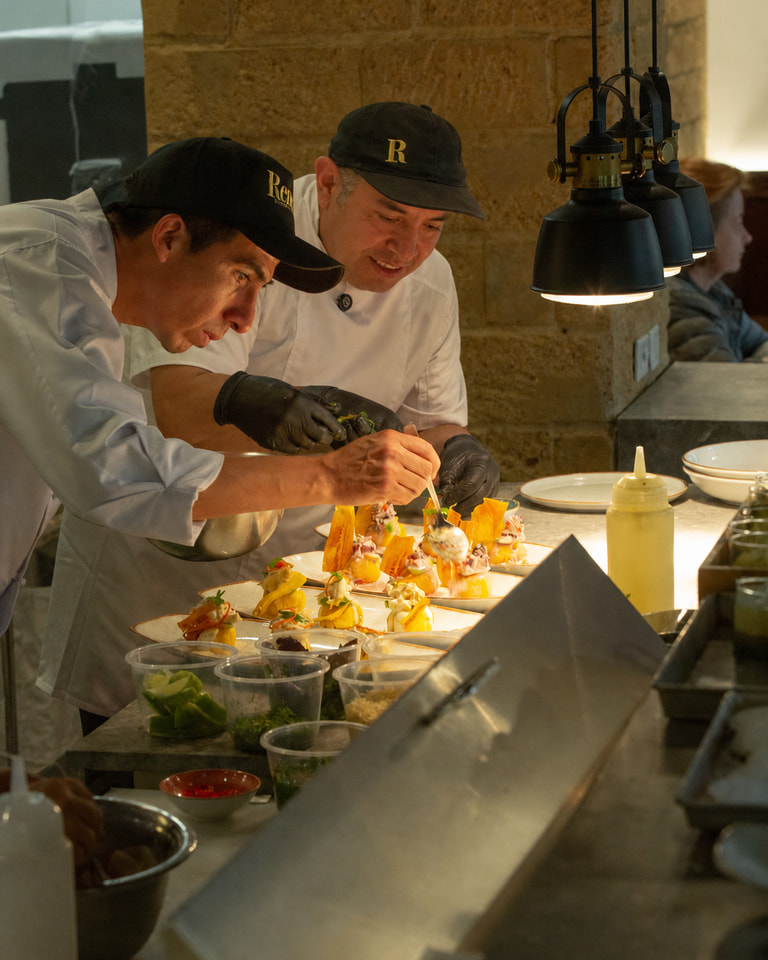 Miguel Ángel Castillo y un auxiliar de cocina trabajan juntos en el emplatado de varios platos en la cocina de Renne.