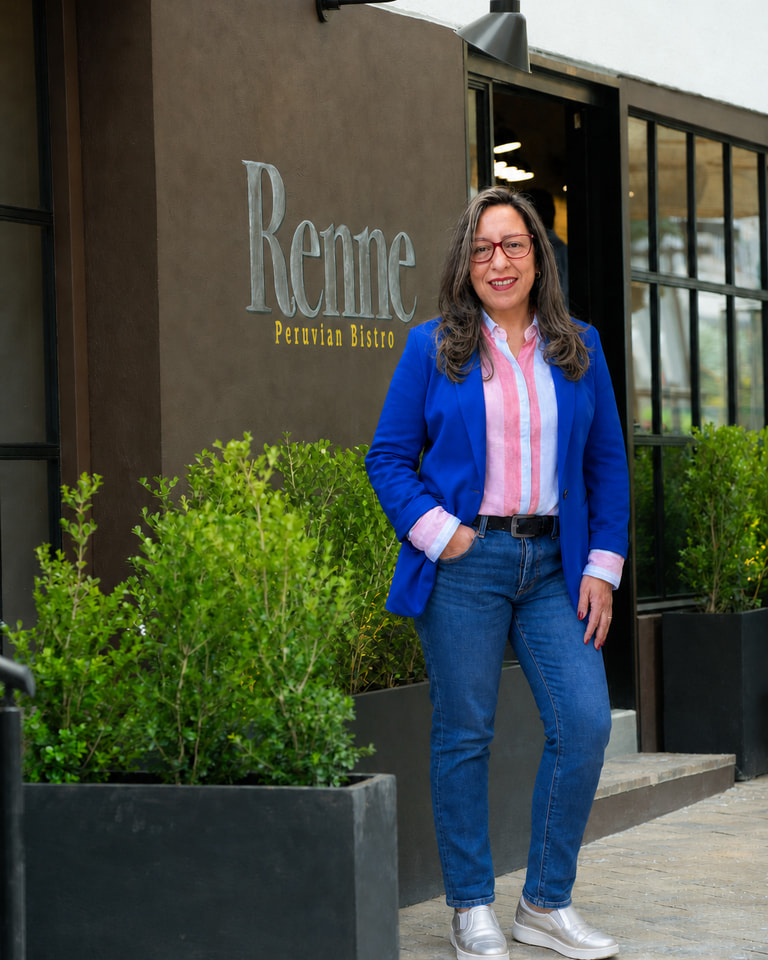 Retrato editorial de Marisol López Rojas, sonriente y de pie junto al rótulo de Renne en la terraza del restaurante.