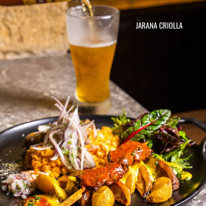 Jarana Criolla de Renne servida con una bebida, papas, ensalada y varias preparaciones peruanas.