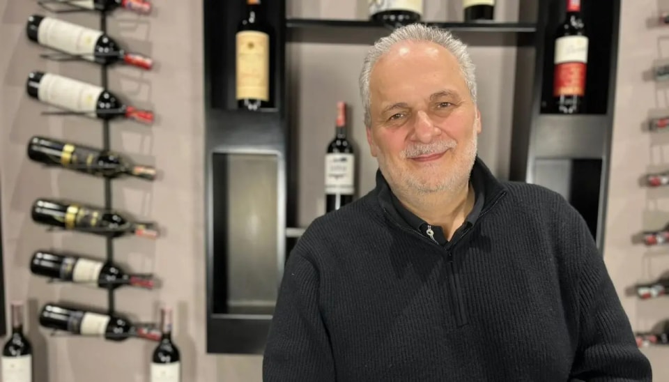 Carlos Renne Cure Lemaitre en un espacio de Renne con botellas de vino al fondo.