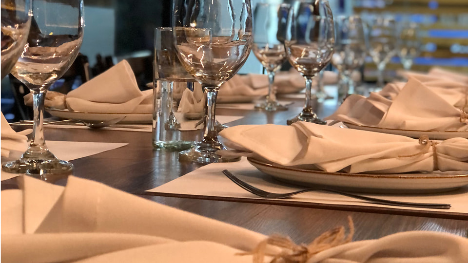 Mesa de Renne preparada con copas, vajilla y servilletas, sin personas, lista para recibir un evento privado.